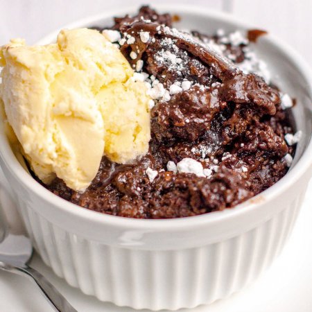 A dish of lava cake with ice cream and a sprinkling of powdered sugar.