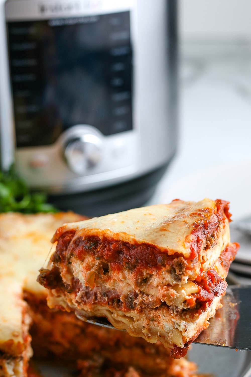 A slice of lasagna being taken out of the finished Instant Pot Lasagna.