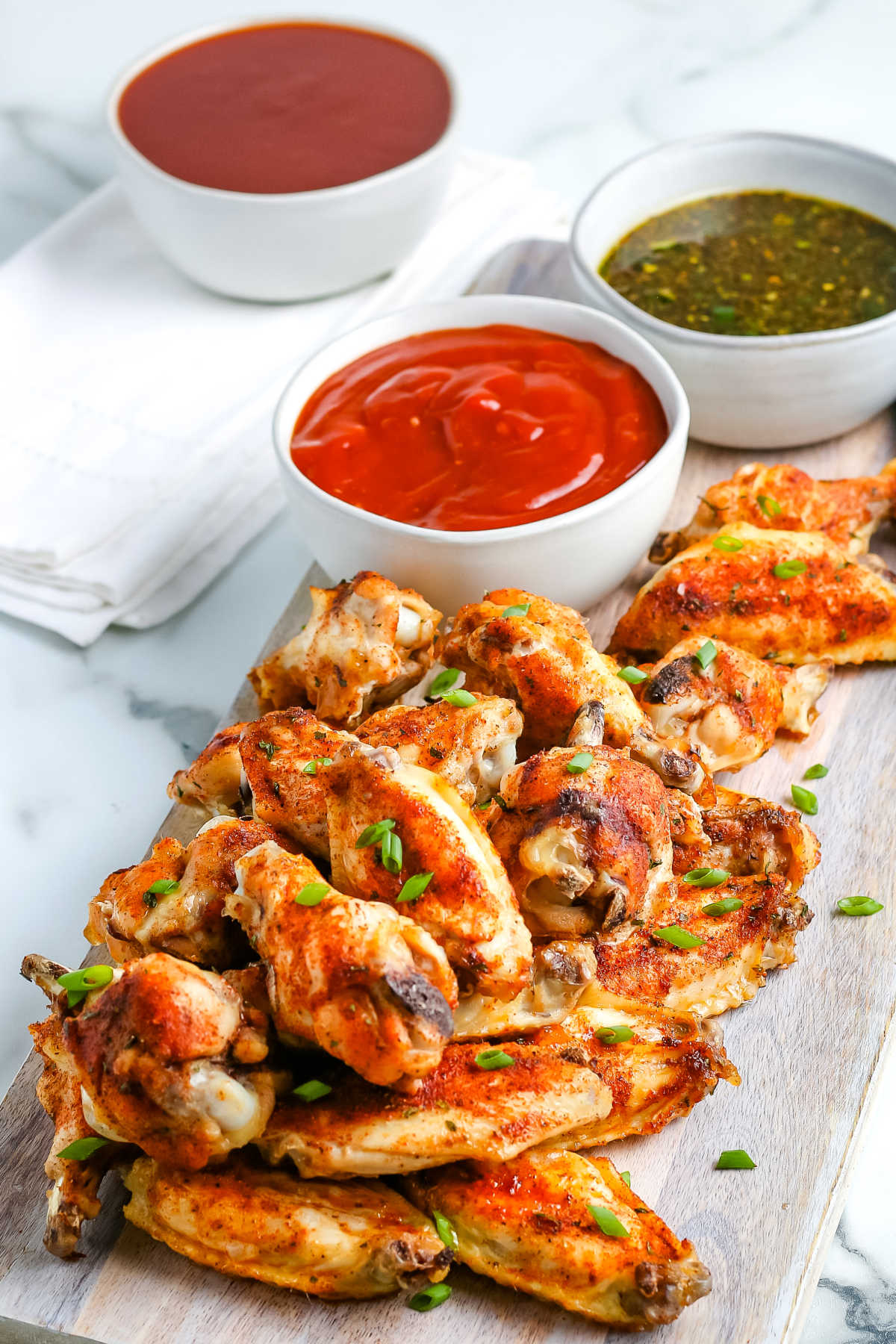 Baked Chicken Wings on a platter with three different dipping sauces.