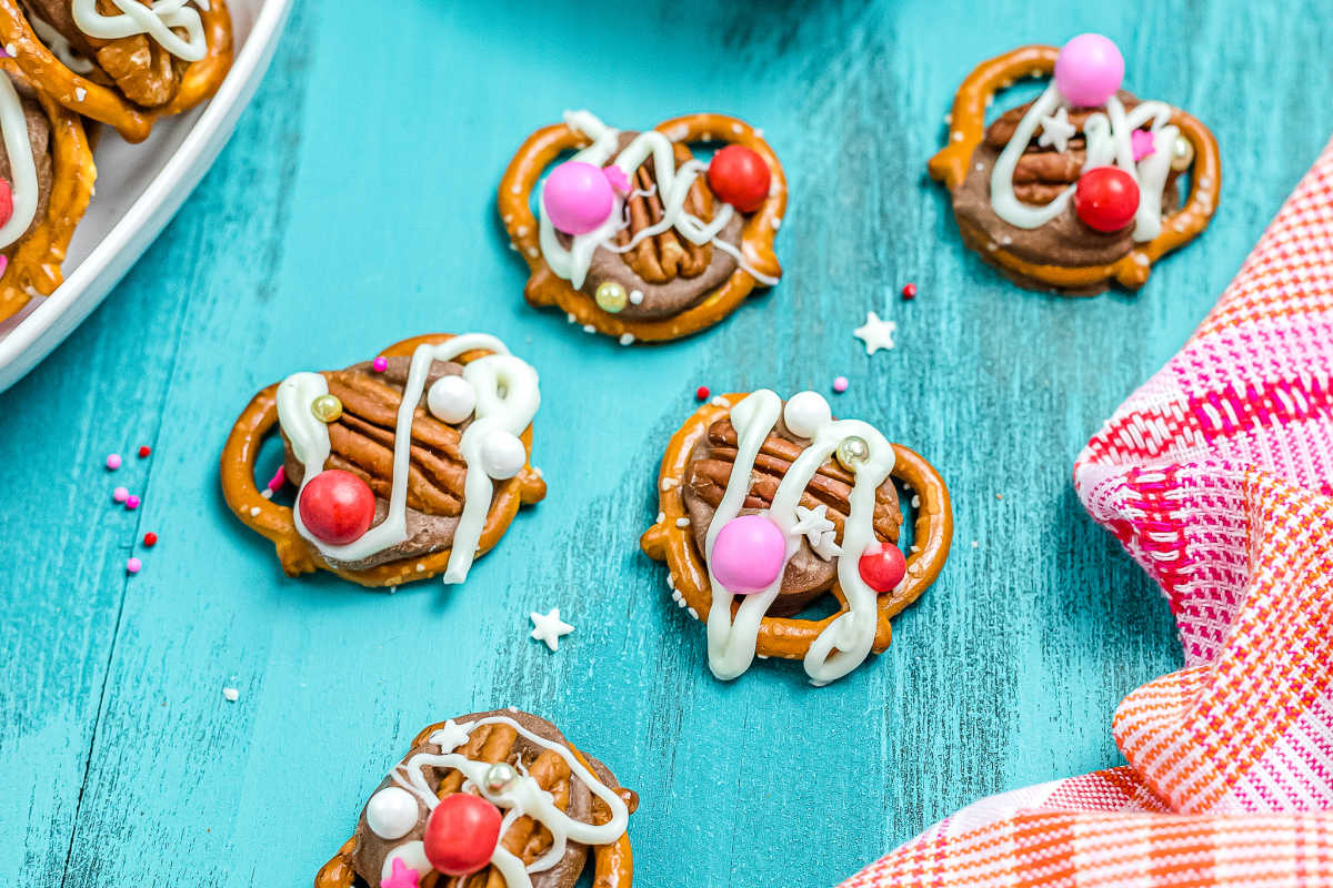 THE FINISHED Valentine's Day Rolo Pretzel Turtles on a blue counter. 