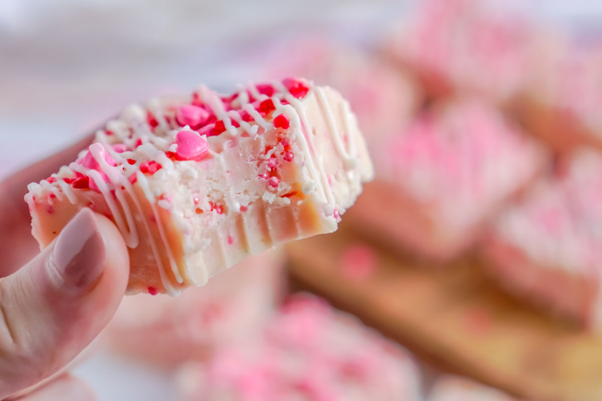 A hand picking up a piece of Valentine's Day Fudge with a bite taken out of it.
