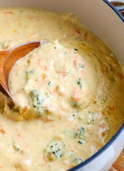 A close up picture of a wooden serving spoon in the finished Broccoli Cheddar Soup.