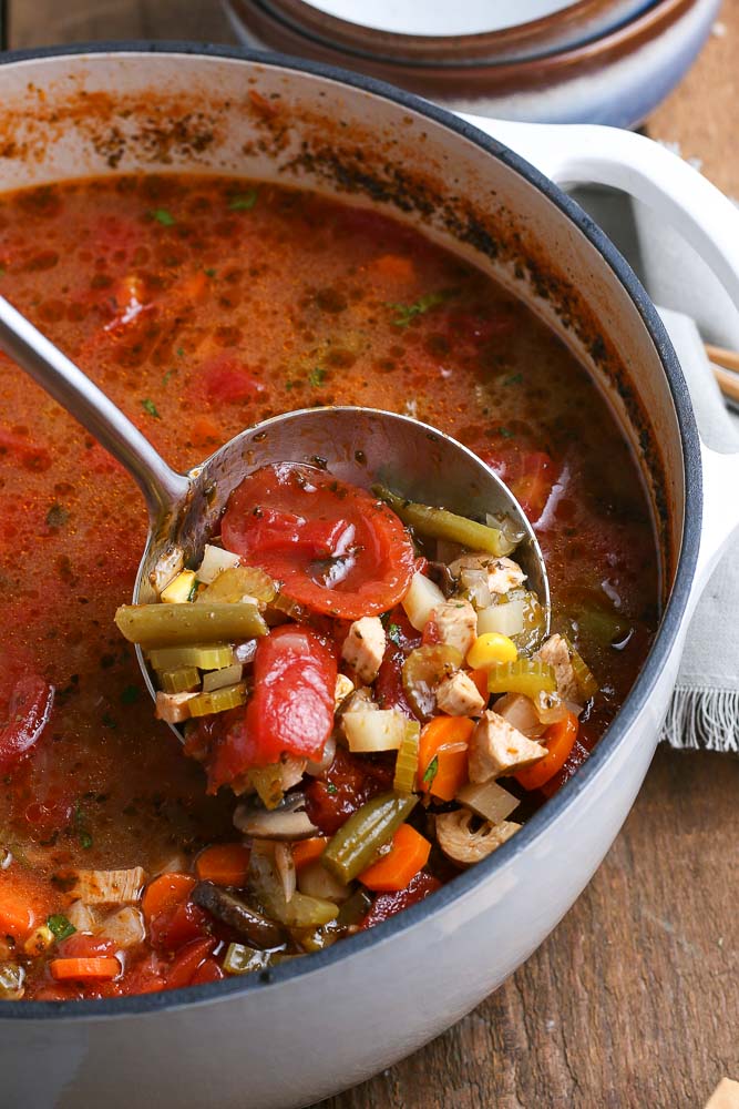 A ladle picking up some Chicken Vegetable Soup. 