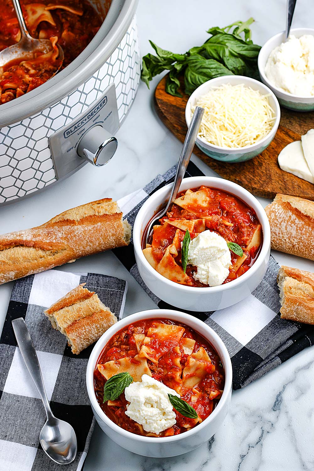 An overhead picture of the finished Crockpot Lasagna Soup in bowls and in a slow cooker in the background.