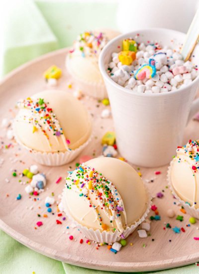 Rainbow White Hot Chocolate Bombs on a platter and in a mug.