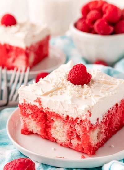 Slices of the finished Raspberry Jello Poke Cake on white plates.