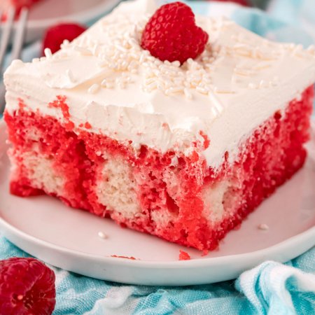 A close up picture of the finished Raspberry Poke Cake on a white plate.