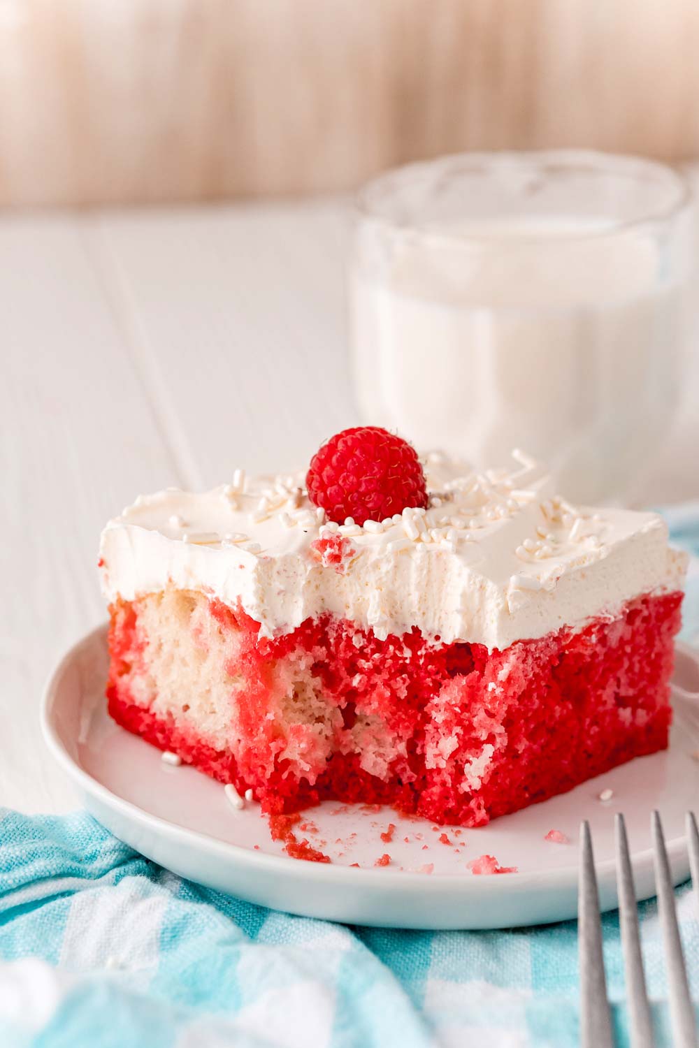 A bite taken out of a slice of Raspberry Poke Cake. 