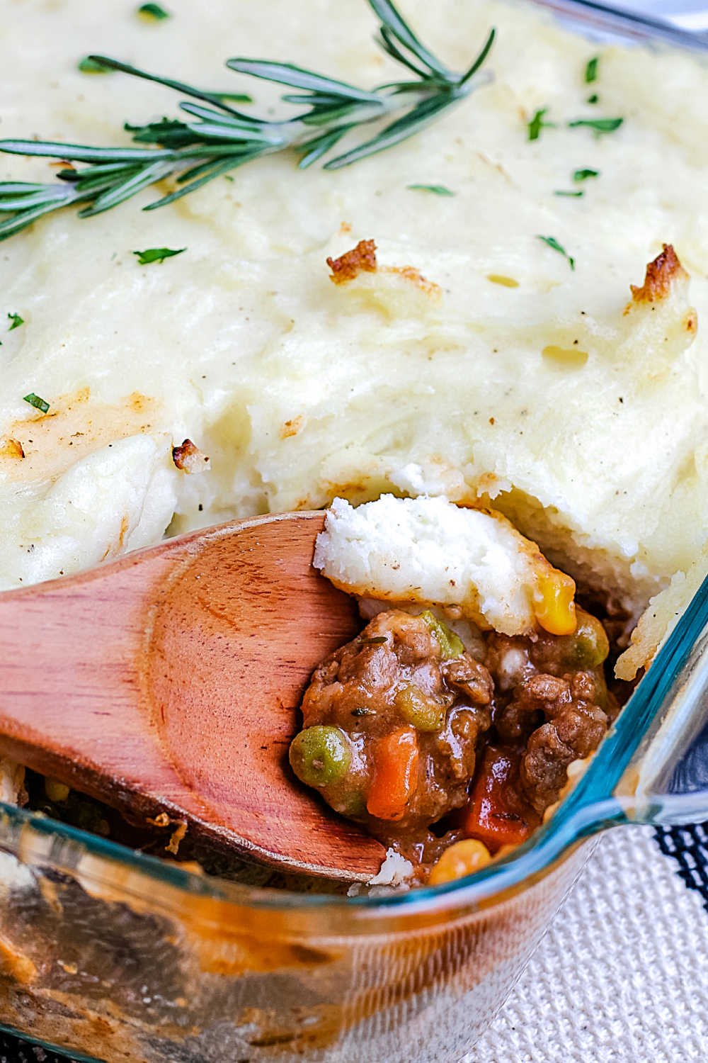 A close up picture of a spoon getting a scoop of shepherd's pie. 