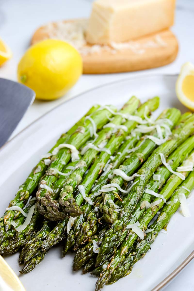 The finished roasted asparagus on a white serving plate.