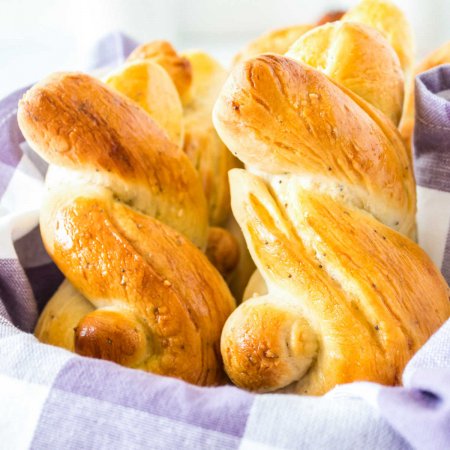 Two Easter Bunny Rolls in a basket with a purple gingham napkin.