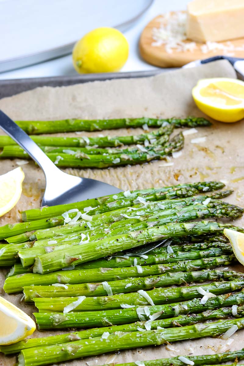 A spatula picking up some roasted asparagus. 