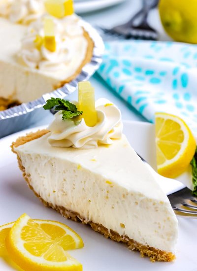 A slice of Lemon Icebox Pie on a plate with lemon slices on a plate.