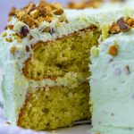 A close up picture of a slice of Pistachio Pudding Cake being cut from the cake.