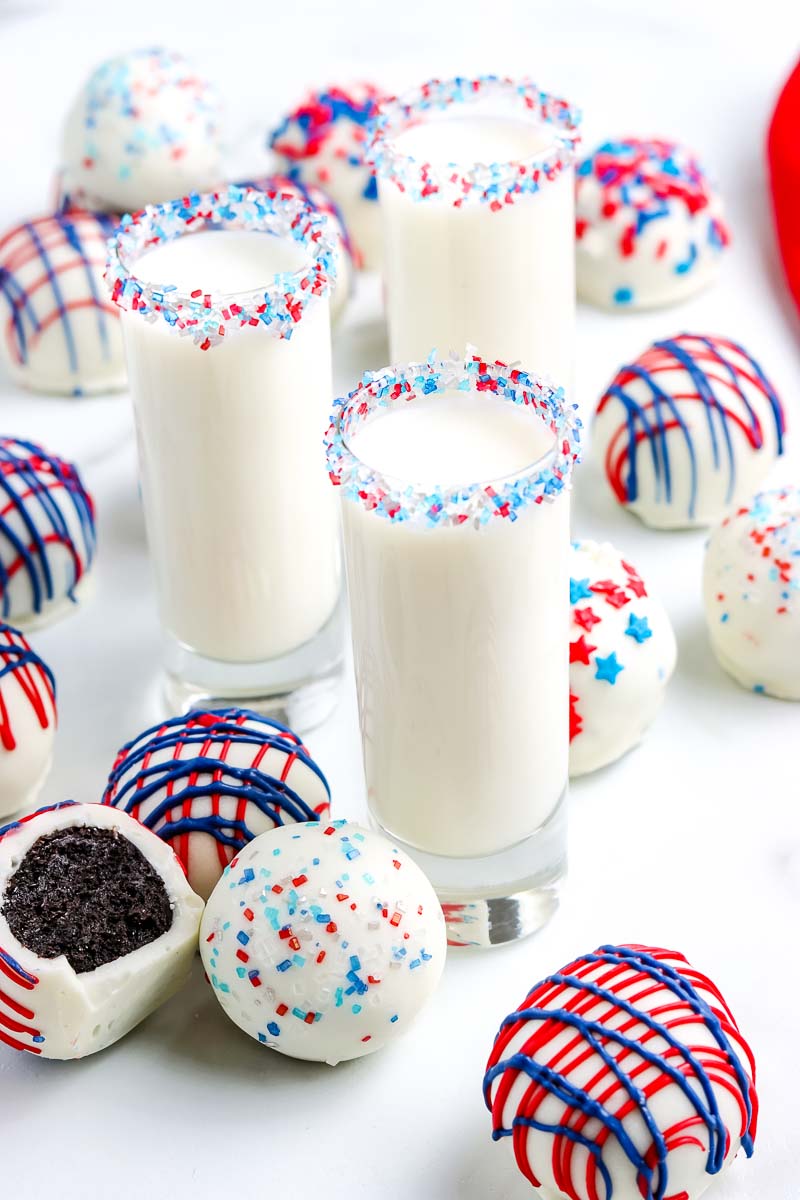 Patriotic Oreo Cream Cheese Truffles with glasses of milk surrounding them.