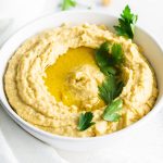 A close up picture of a bowl of hummus drizzled with olive oil.
