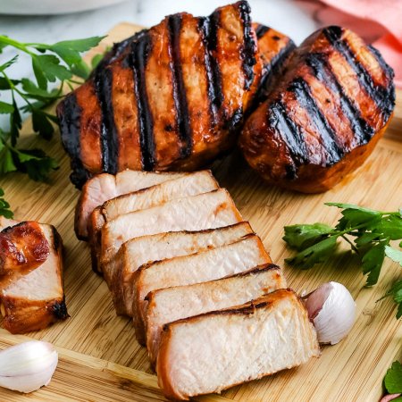 A close up picture of sliced pork chops on a wooden cutting board.