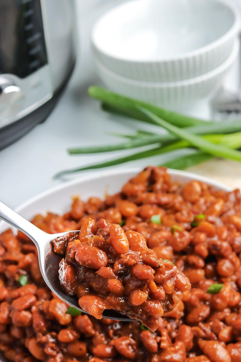 A spoon picking up some of the Instant Pot Baked Beans.