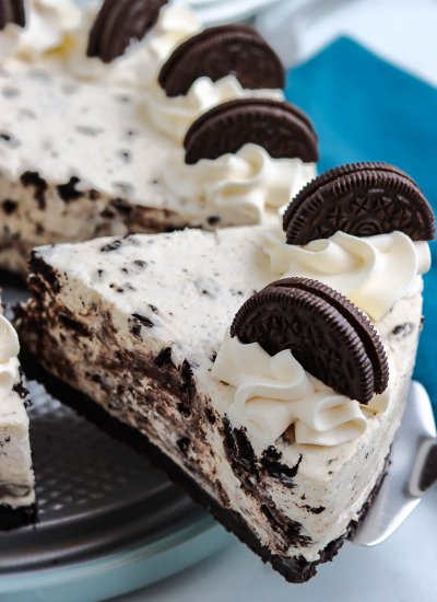 A slice of No Bake Oreo Cheesecake being taken out of the bigger cake.