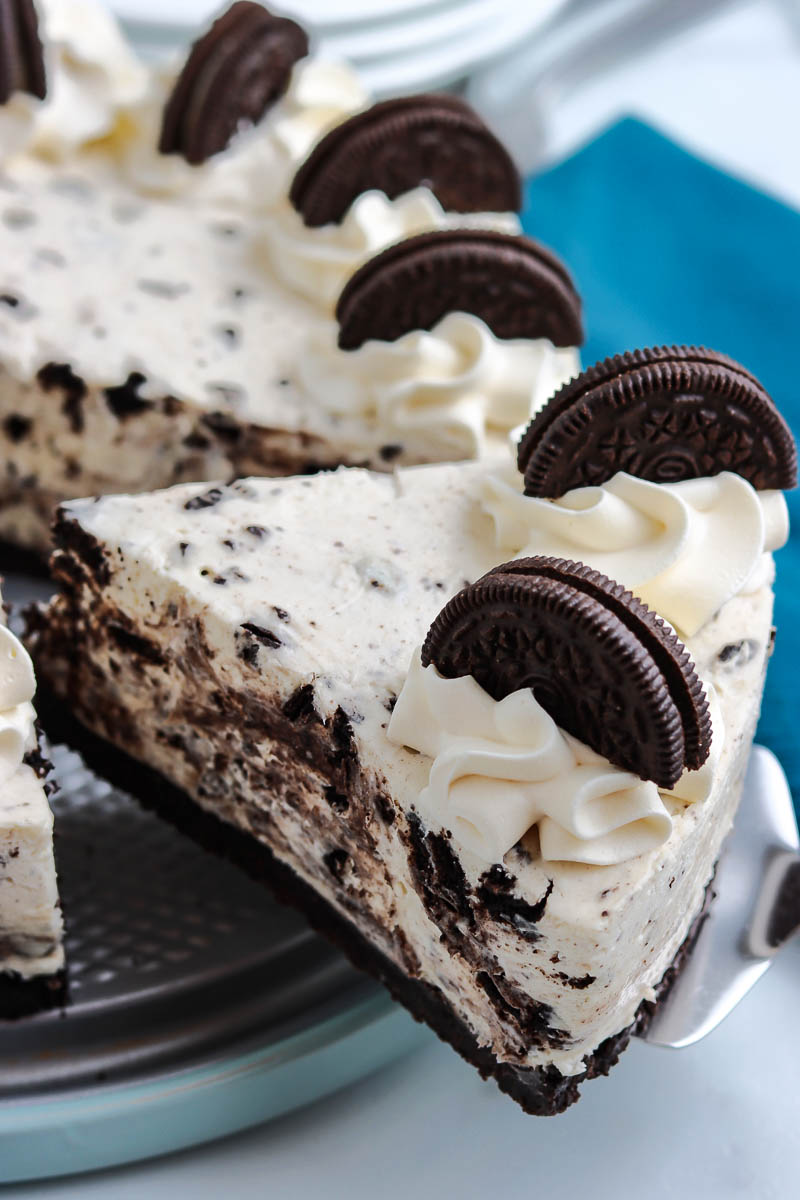 A slice of No Bake Oreo Cheesecake being taken out of the bigger cake. 