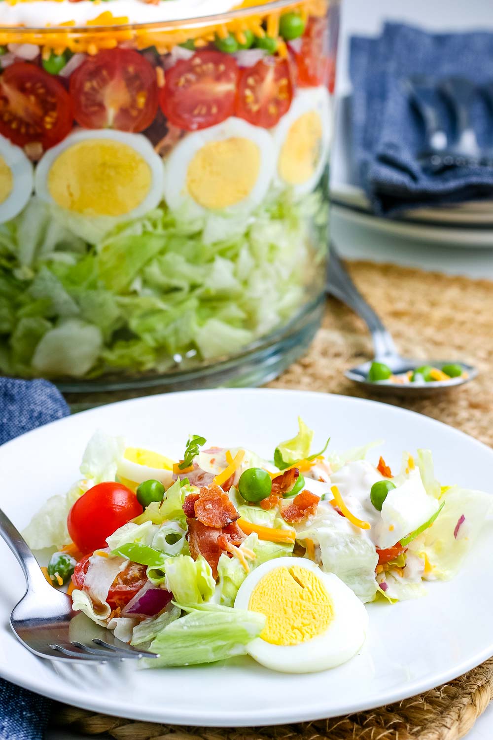7 Layer Salad on a white plate and in a trifle dish in the background.