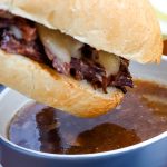 An Instant Pot French Dip being dipped into au jus.