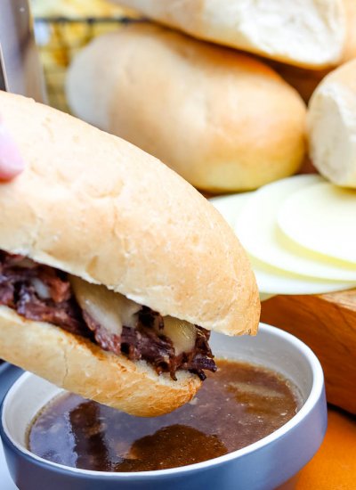 A French Dip Sandwich being dipped into au jus.