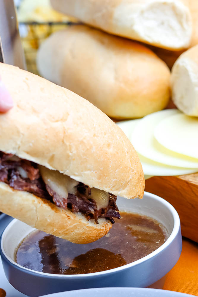 A French Dip Sandwich being dipped into au jus.