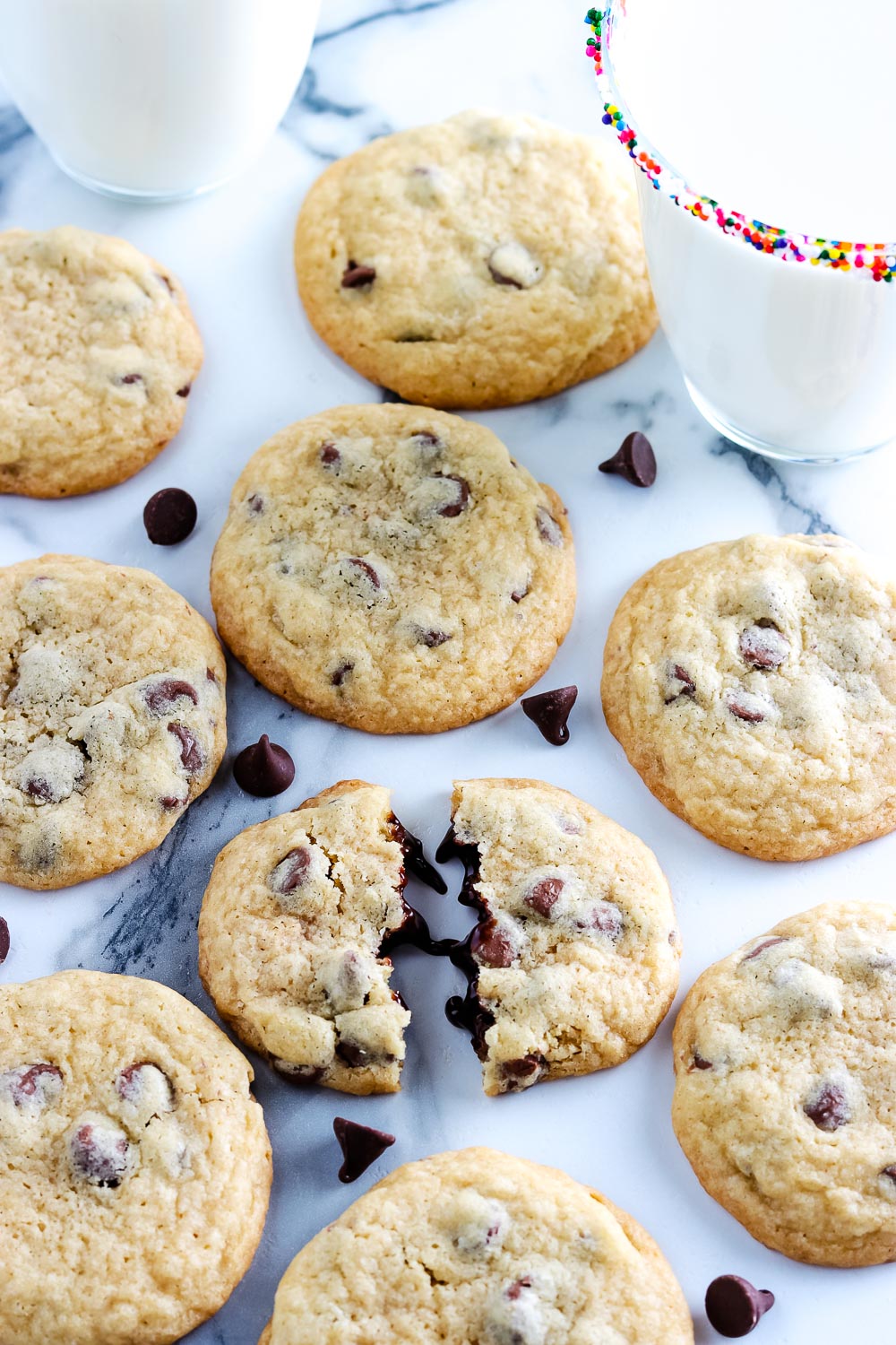 Copycat Mrs. Field's Chocolate Chip Cookies on a marble counter tip with a glass of milk nearby. 