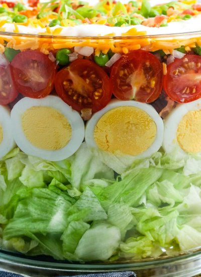 A close up picture of a 7 Layer Salad in a trifle serving dish.