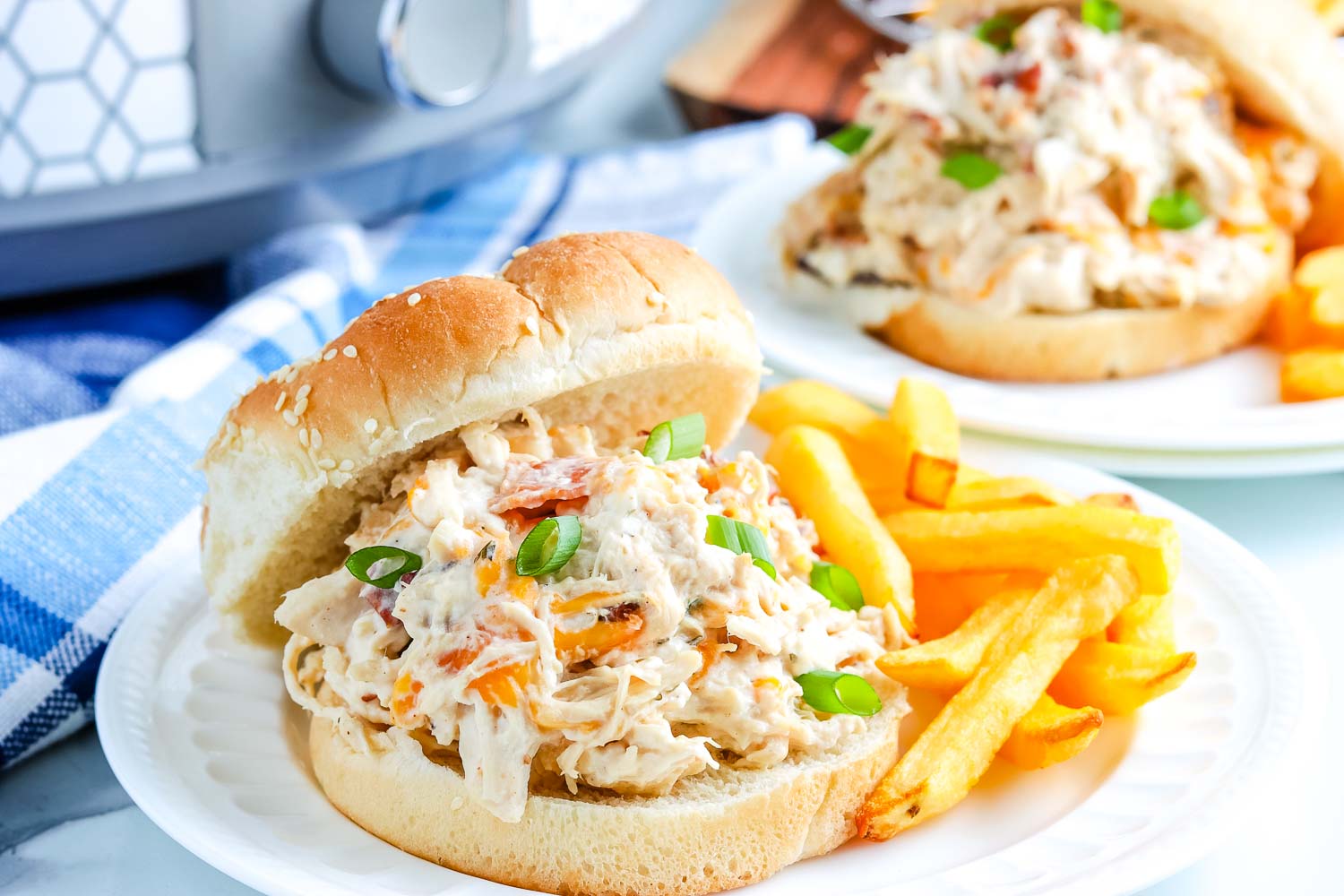 Shredded Crack Chicken on a hamburger bun garnished with chopped green onion.