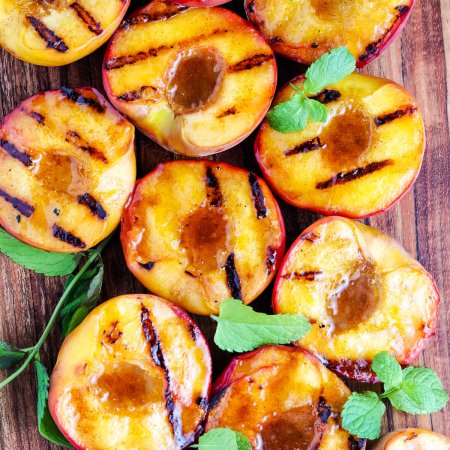 A close up overhead picture of Grilled Peaches on a wooden cutting board.
