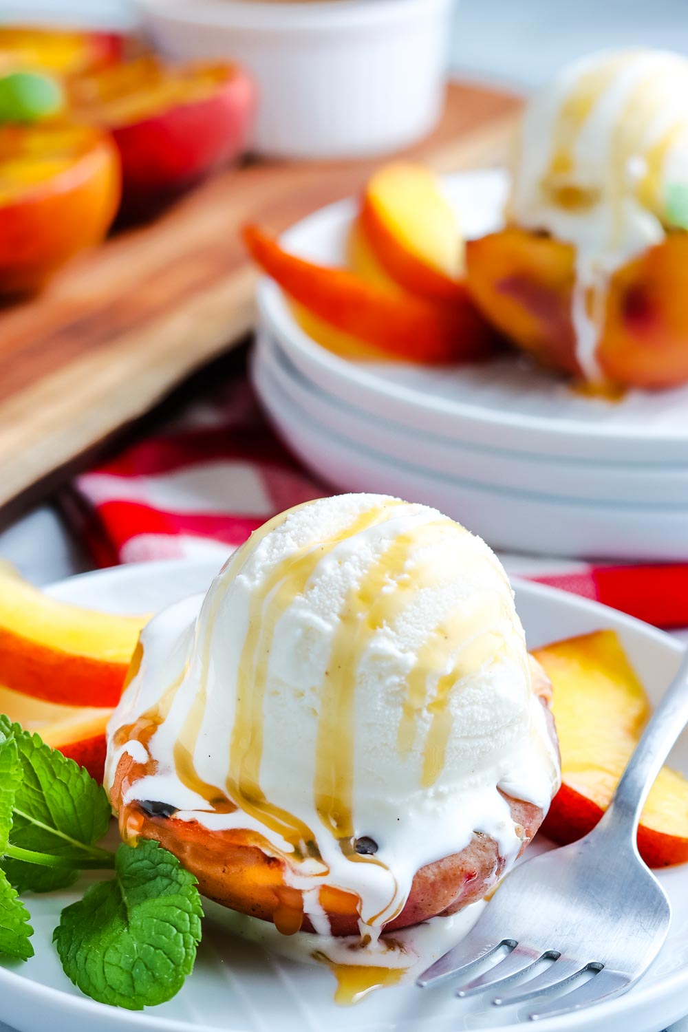 A grilled peach with a scoop of ice cream and caramel sauce.