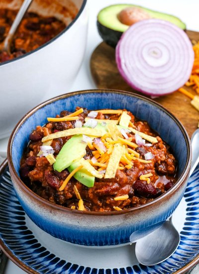 A bowl of Ground Turkey Chili with the white pot in the background.