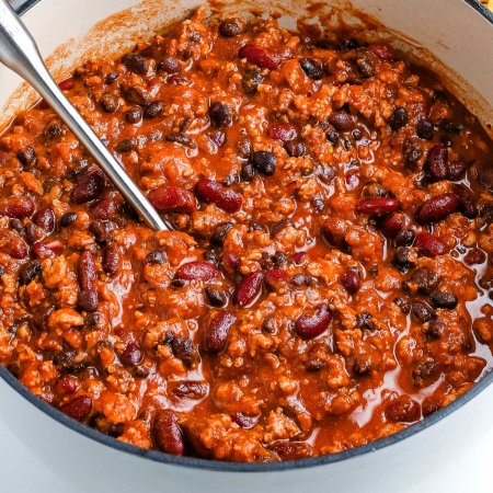 A close up picture of Ground Turkey Chili in a white cast iron pot.
