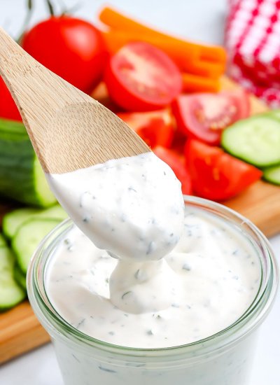 A wooden spoon dipping into Homemade Ranch Dressing.