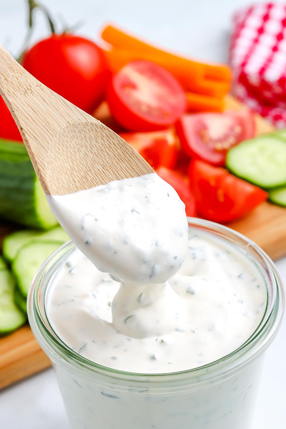 A wooden spoon dipping into Homemade Ranch Dressing. 
