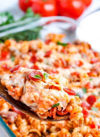A close up picture of a spoon lifting up some of the pizza casserole out of the casserole dish.