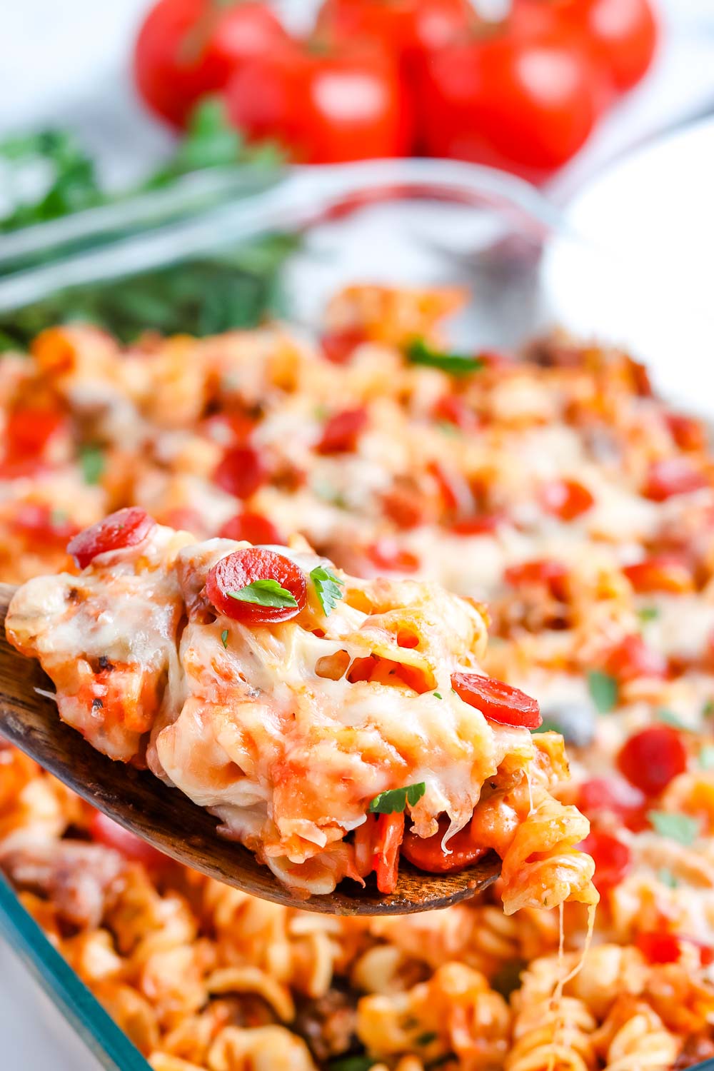 A close up picture of a spoon lifting up some of the pizza casserole out of the casserole dish. 