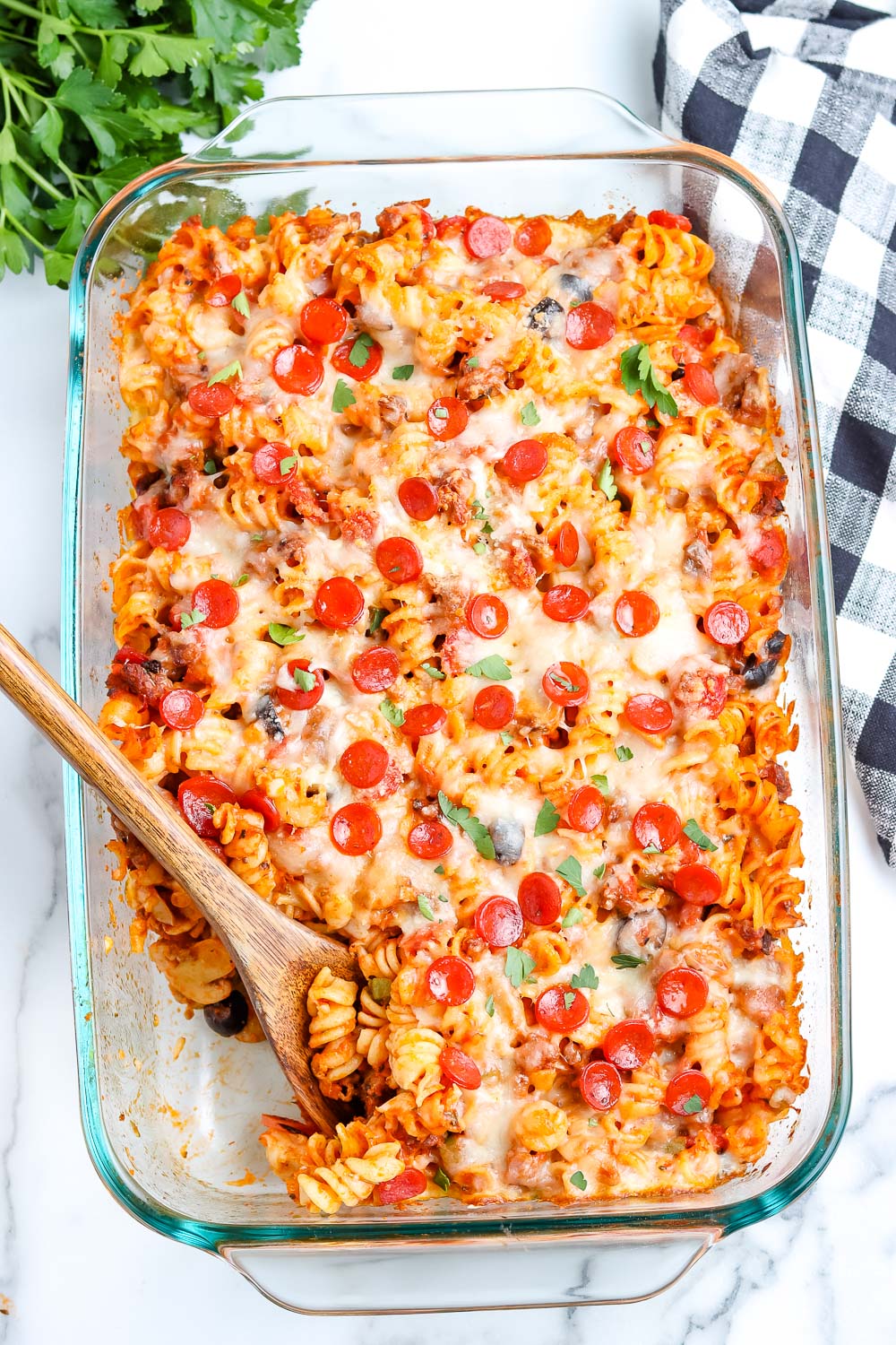 An overhead picture of the finished Pizza Casserole with a wooden spoon in the casserole dish.