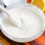 A close up picture of the finished Homemade Ranch Dressing in a clear class mixing bowl.