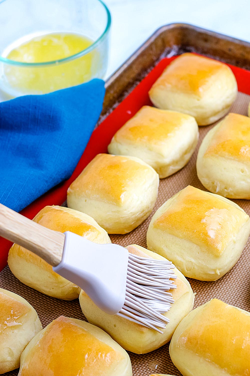 Butter being brushed on top of the finished rolls. 