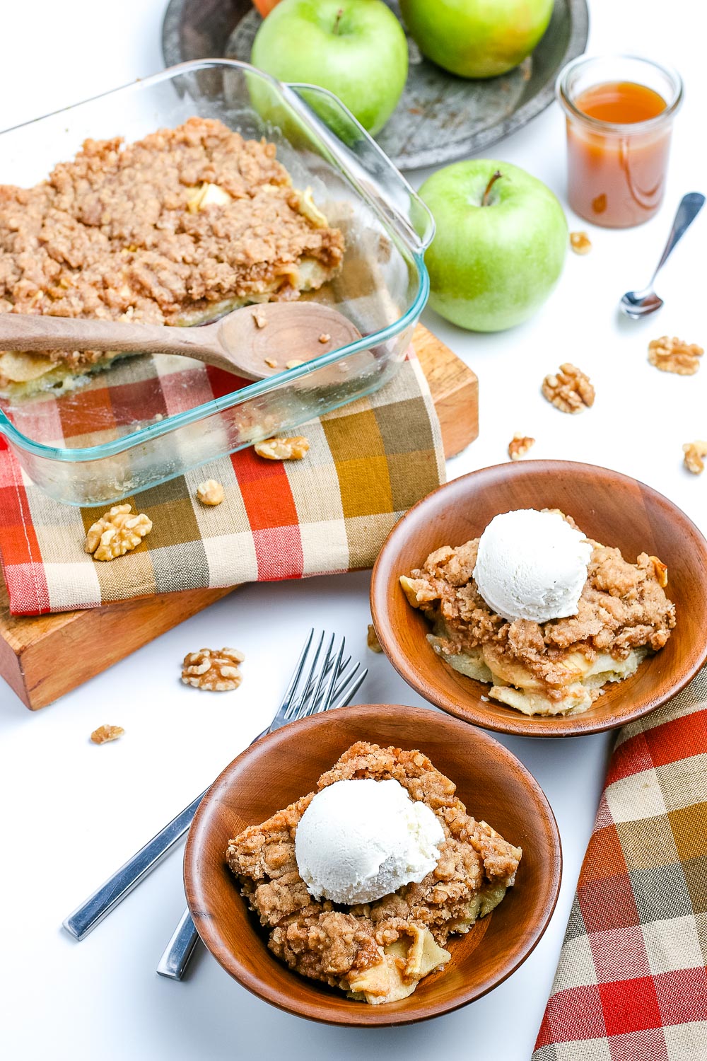 Easy Apple Crisp in a backing dish and in wooden bowls with ice cream on top. 