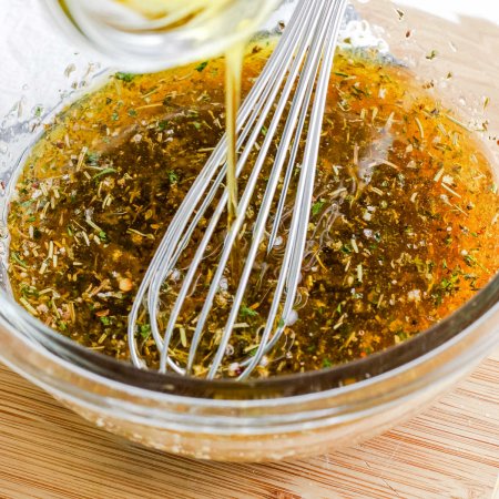 A close up picture of Italian dressing in a mixing bowl that is being whisked.