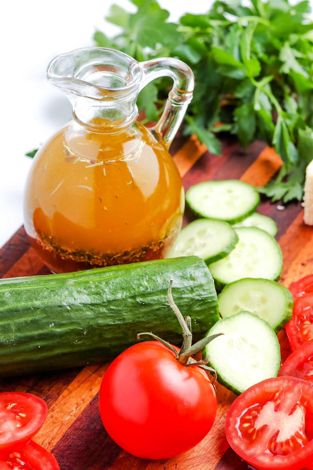 Homemade Italian Dressing in a glass bottle and veggies on a cutting board.