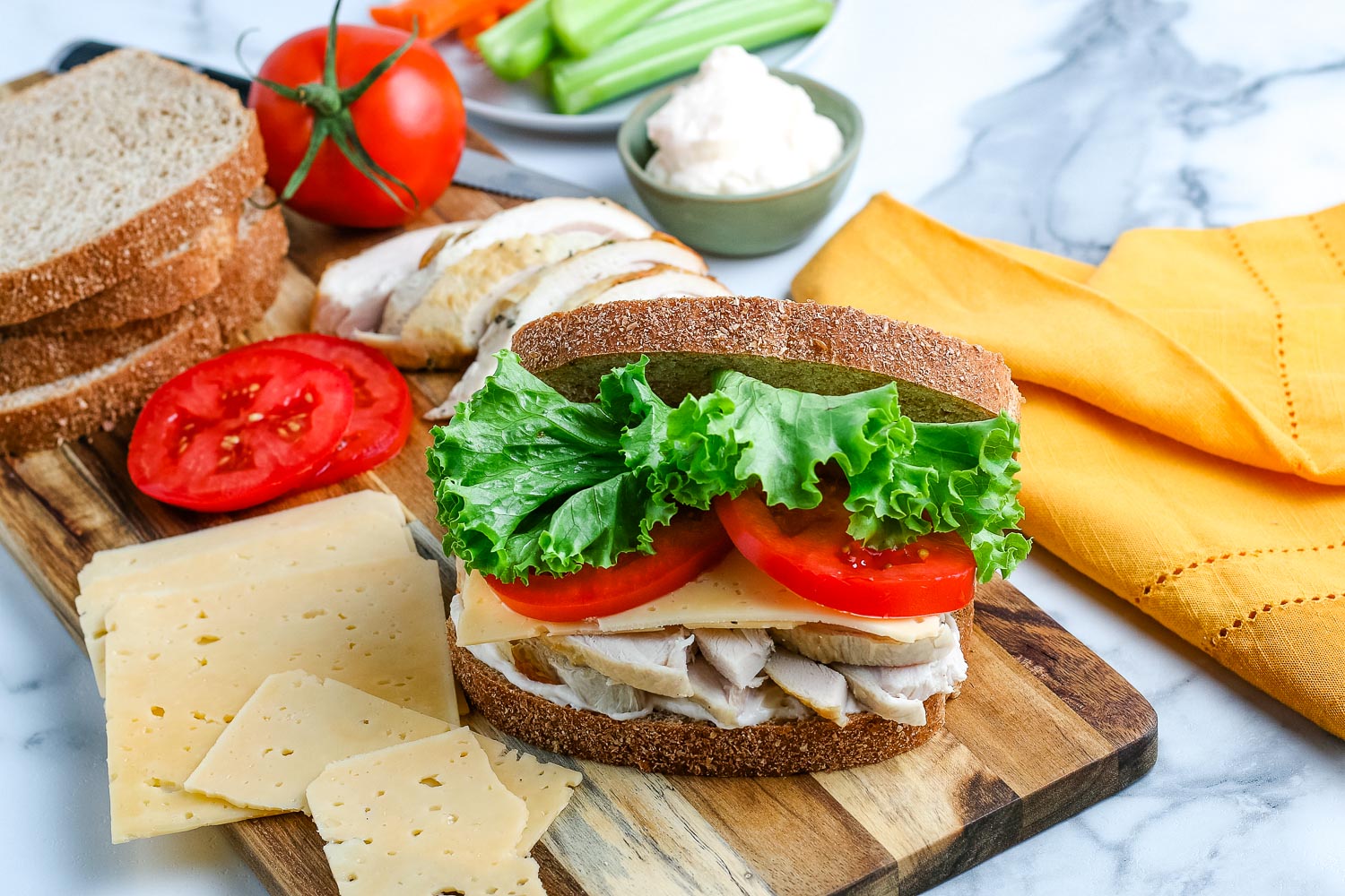 Leftover Turkey Sandwich on a wooden cutting board surrounded by other sandwich ingredients.