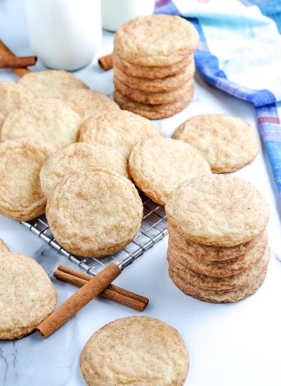 The finished Snickerdoodle Cookies stacked on top of each other and on a wire cooling rack.