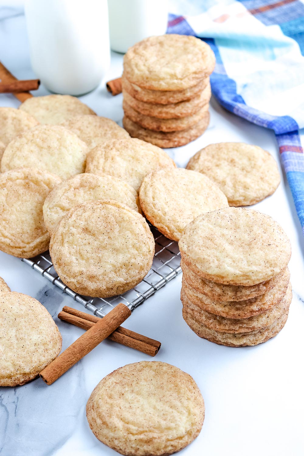 The finished Snickerdoodle Cookies stacked on top of each other and on a wire cooling rack.