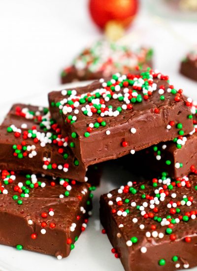 Christmas Fudge stacked on a platter with festive sprinkles on top.