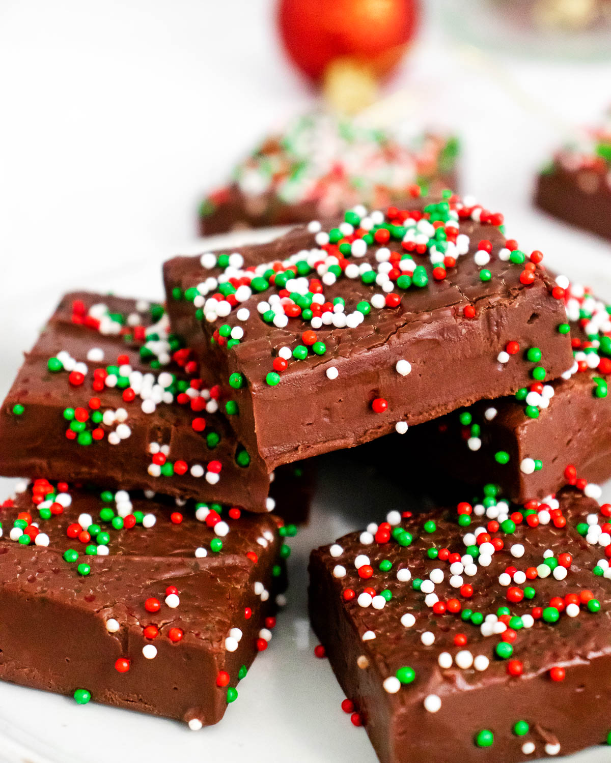 Christmas Fudge stacked on a platter with festive sprinkles on top.